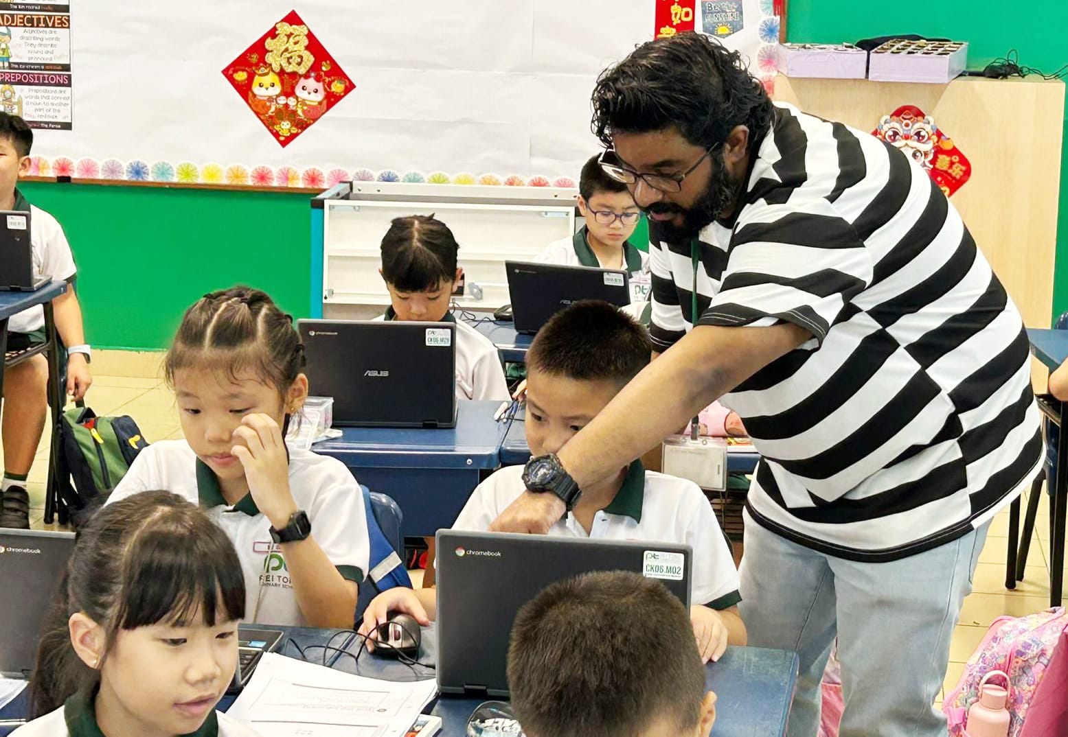 A teacher guides students as they use Chromebooks during a digital competencies lesson, building confidence in using technology to solve problems and complete learning tasks.